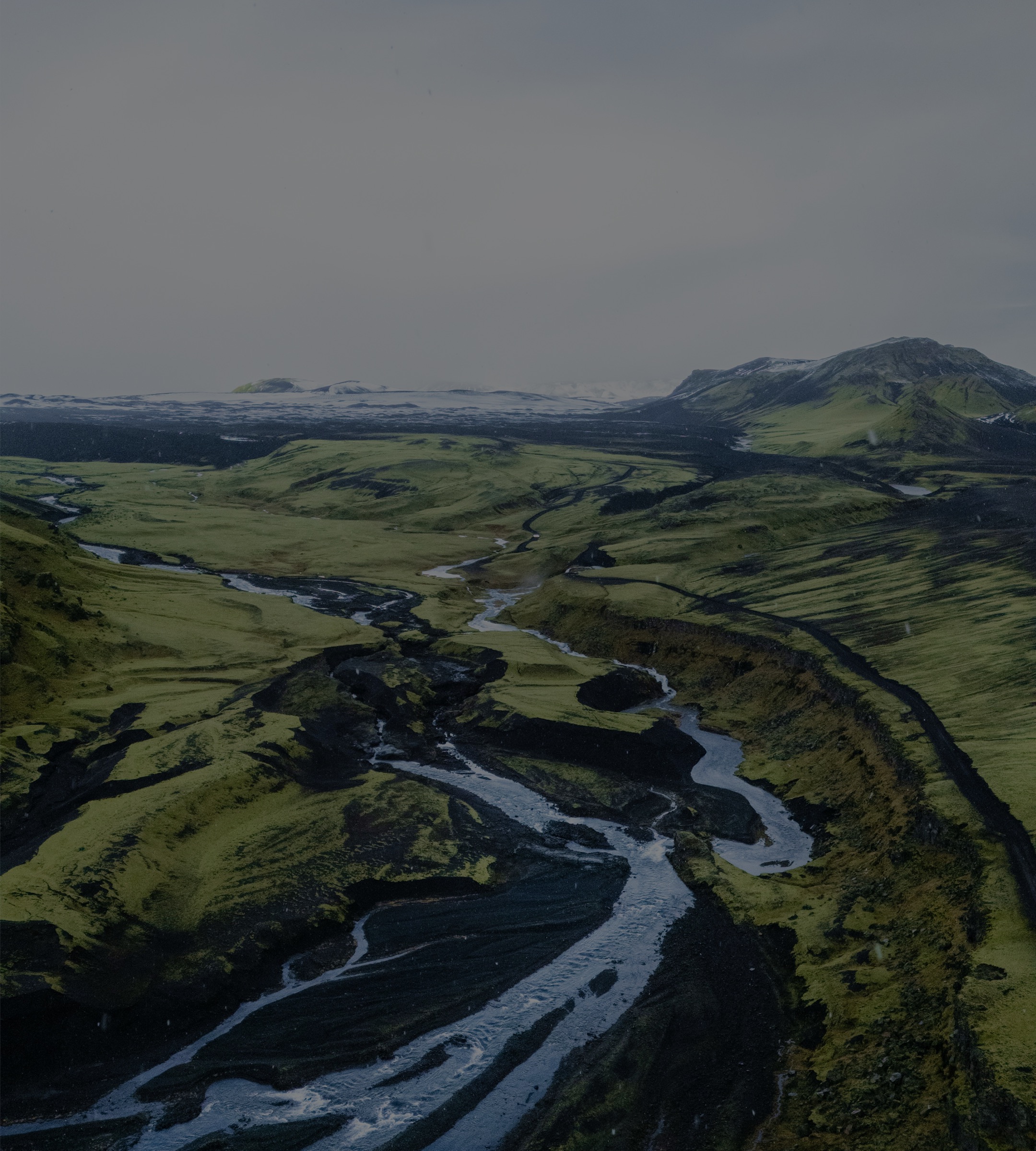 A glacial river braiding across a green valley, seen from the air